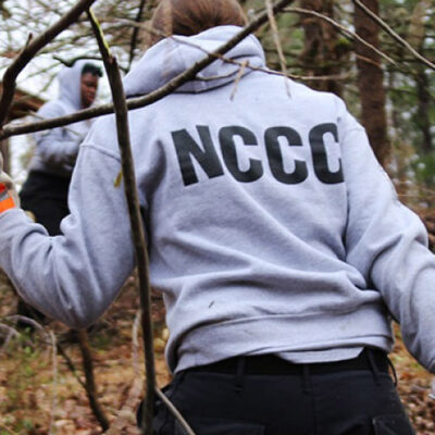 A NCCC worker hauling branches