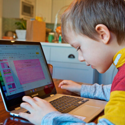 A young child works at home remotely on an online class assignment.