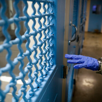 A gloved hand points to a holding cell in a Los Angeles jail.
