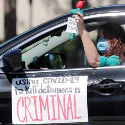 A woman drives in a caravan protesting conditions detainees face in ICE detention centers.