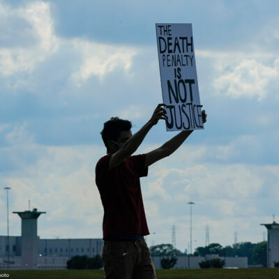 A death penalty protestor carries a sign that reads "the death penalty is not justice."