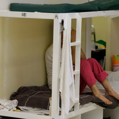A detainee sits on a bunk in a women's area at an immigration detention center.