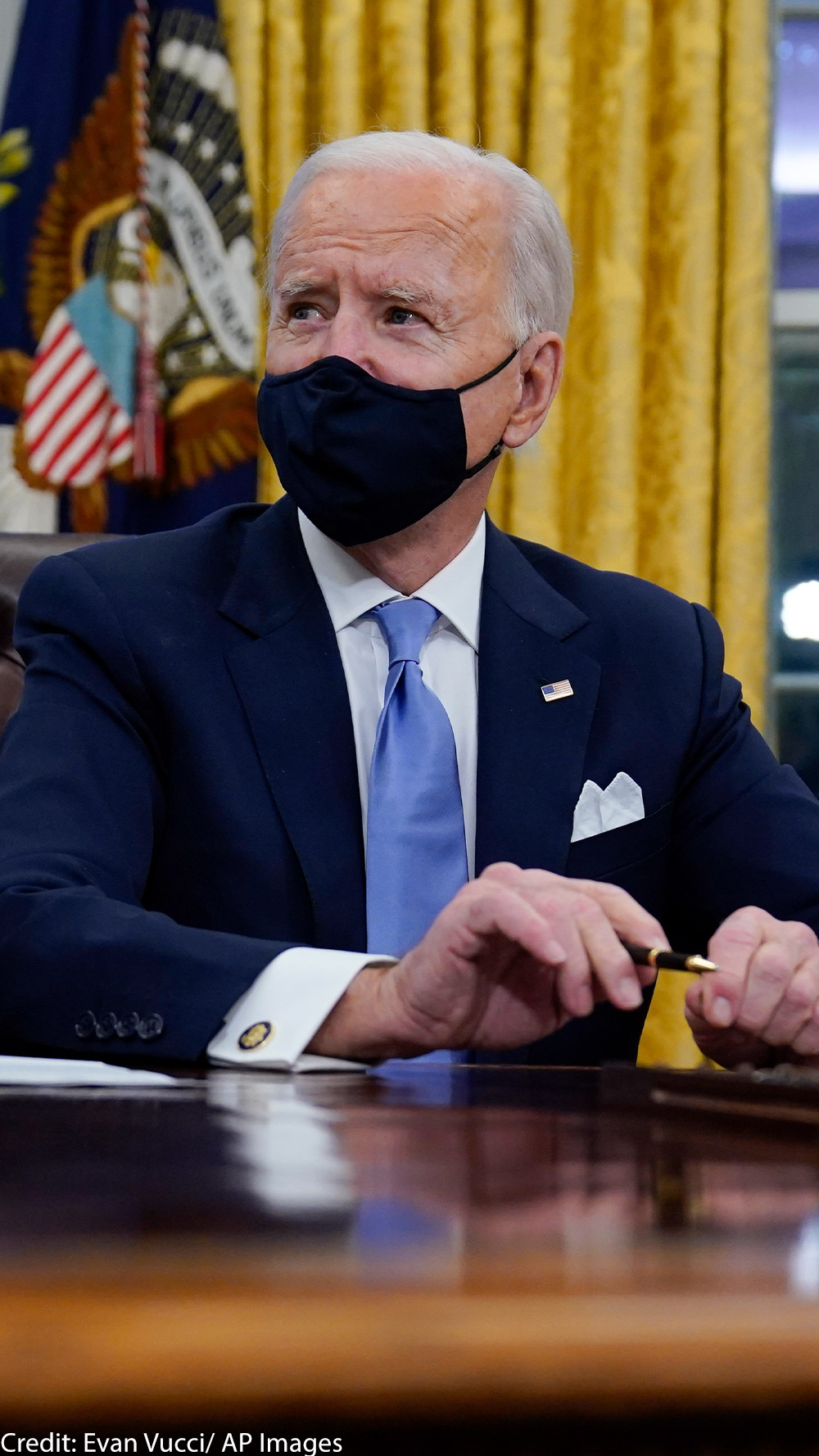 A photo of President Biden in the Oval Office wearing a mask.