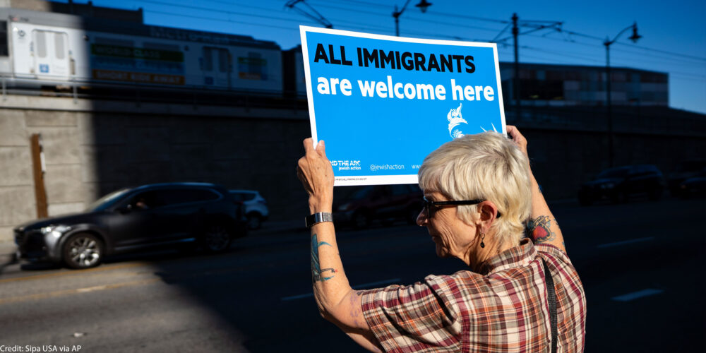 A protestor holds a sign that says All Immigrants Are Welcome Here.