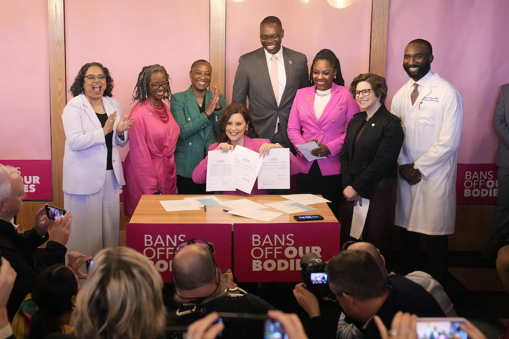 Governor Gretchen Whitmer holding up a signed repeal of an abortion ban.