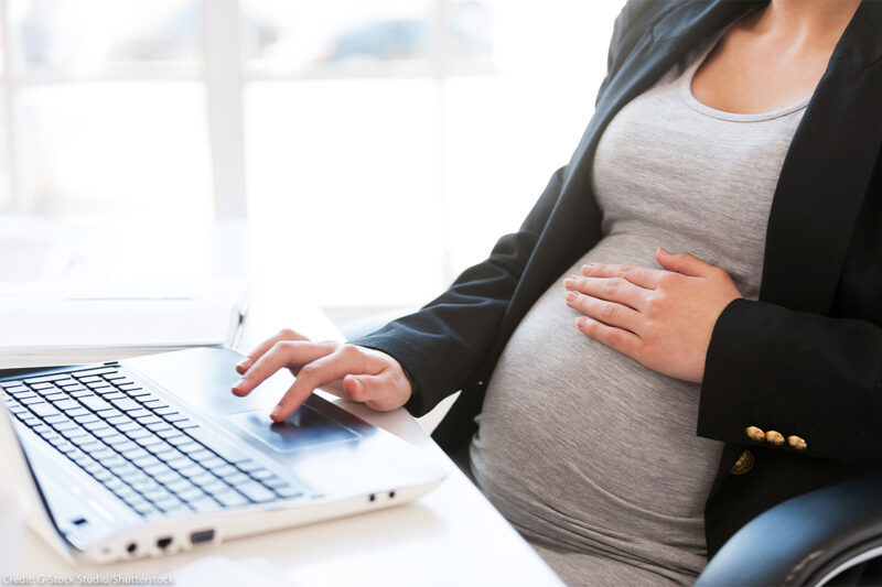 Pregnant businessperson working on laptop.