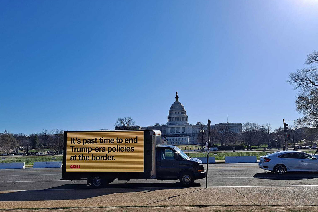 A truck with a digital sign on its side saying, "It's past time to end Trump-era policies at the border."