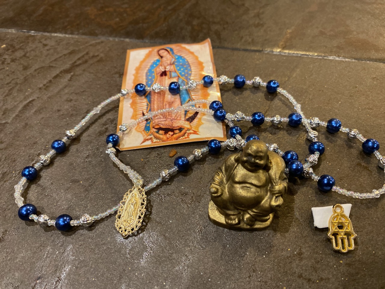 A pile of religious items, including a small Buddha statue and an image of the Virgin Mary.