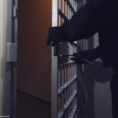 A cell door in a prison being locked by a gloved officer.