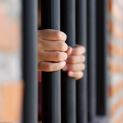 An individual holing on to prison bars.