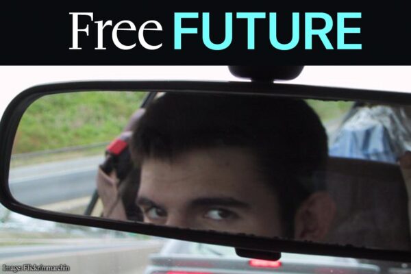 Man looking in car rear-view mirror, warily